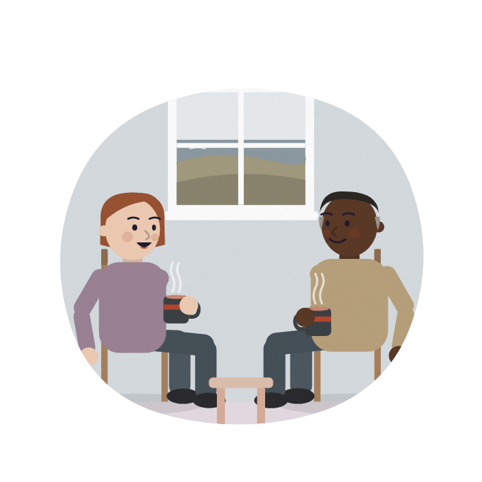 A woman talks with a carers' centre worker over two mugs of tea.