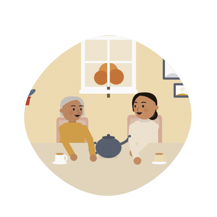 A daughter and her mum share a pot of tea at the mum's kitchen table, laughing.