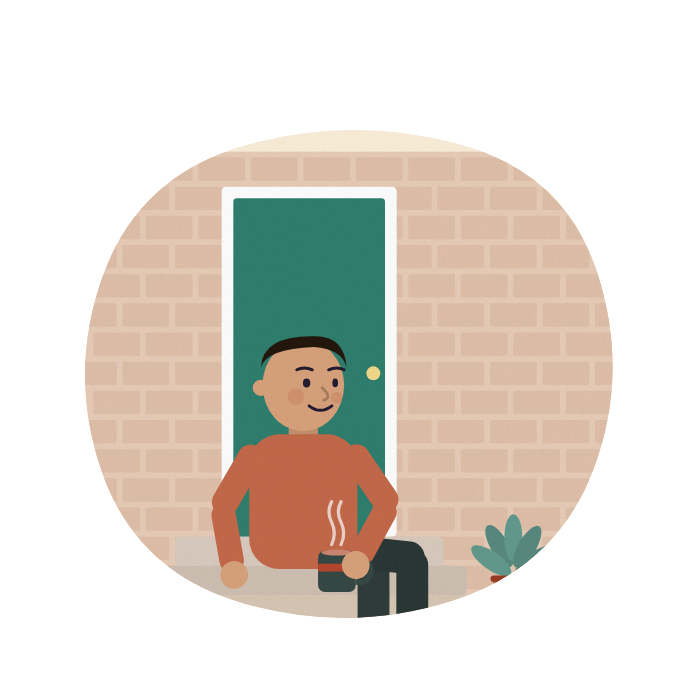 A young man sits on the front step with a mug, taking a breather in the sun.