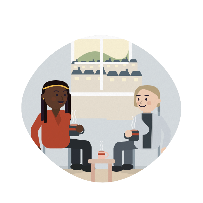A woman talks with a carers' centre worker over two mugs of tea.